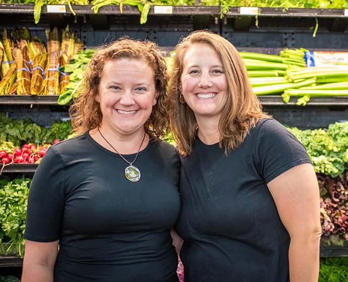 Two people standing in front of produce