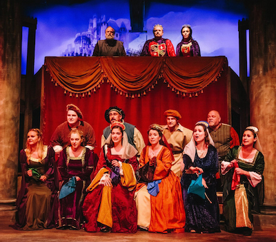 The cast of Camelot dressed in costume, on stage. Front row, Luciana Piazza (3rd from the left), Maria Reed (4th from the left). Back row, Billy Robinson (1st from the left).