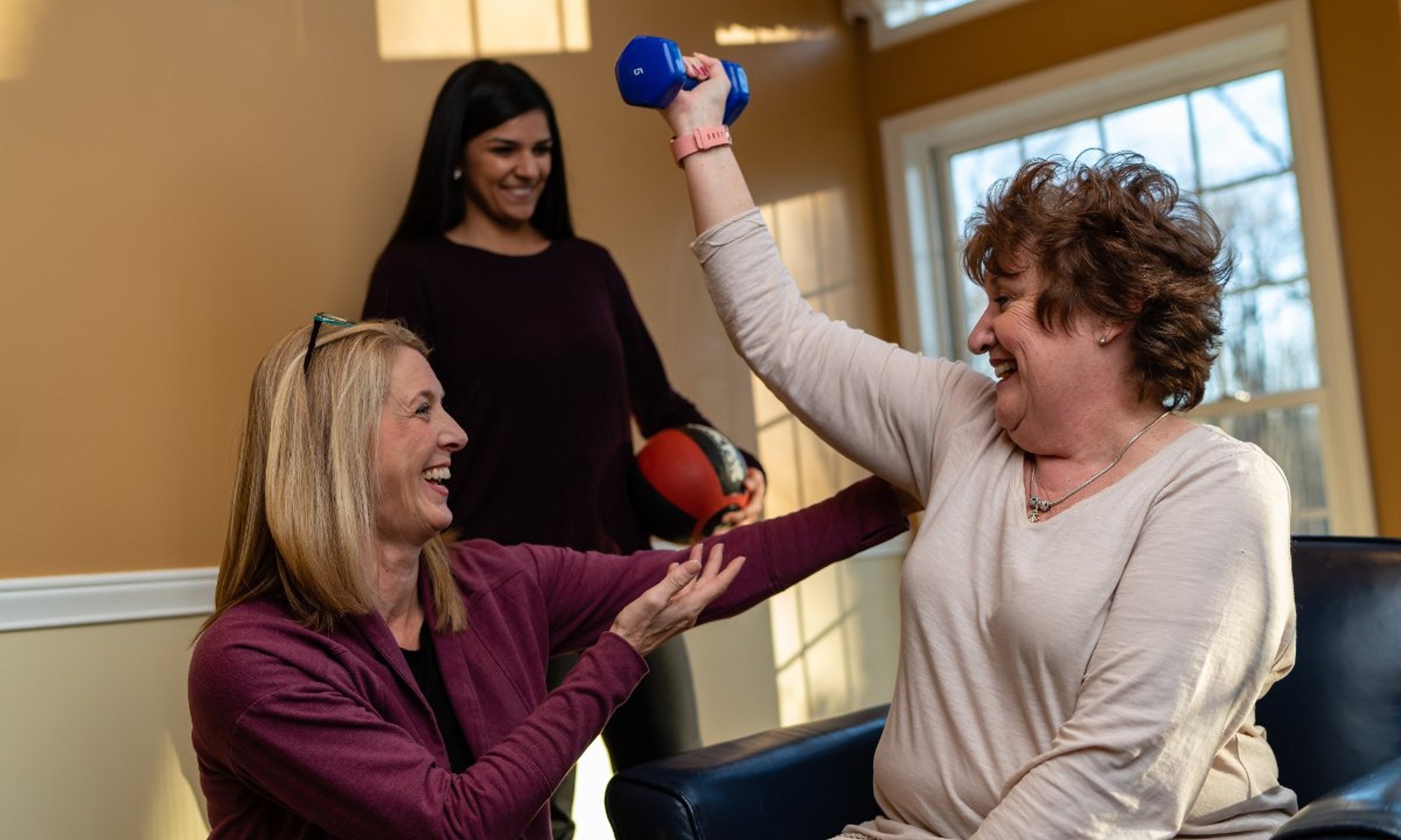 Physical therapy professor and student with woman holding weight