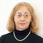 woman in a black turtle neck shirt and glasses, looking at the camera