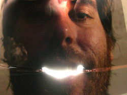 headshot of a man with a light in his mouth
