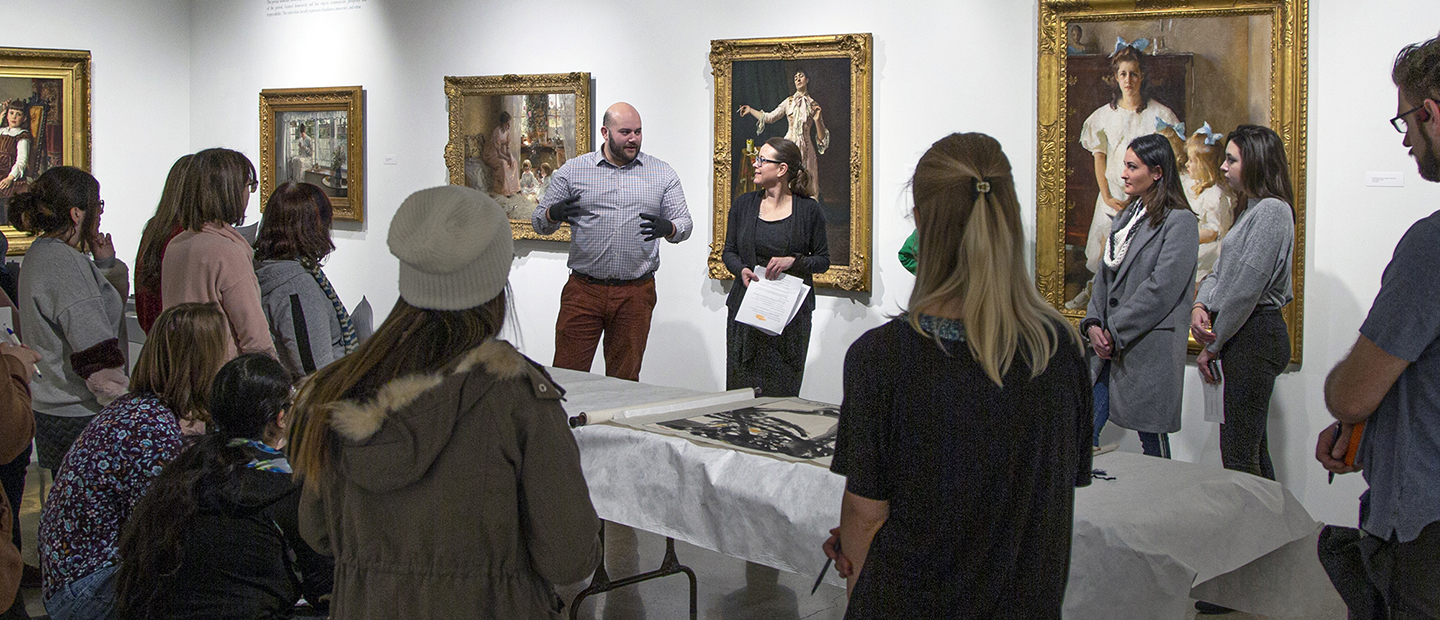 image of a group of people standing in an art gallery listening to a speaker