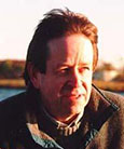 A headshot of Doug Hunter standing outside, looking towards the sun.