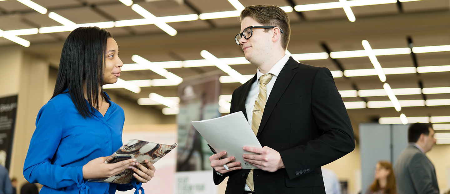 Image of an employer talking with a student at a fair. 