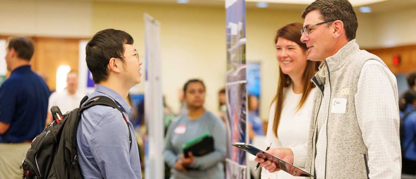 A student talking to employers at a career fair.
