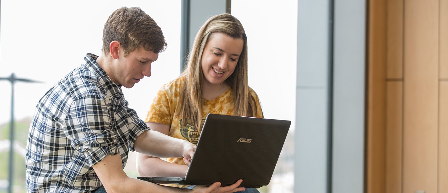 young man and woman looking at something on a laptop together