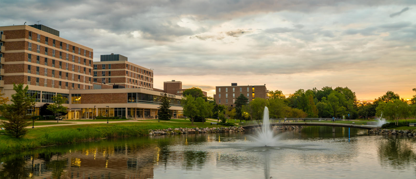 Bear Lake with a fountain in the middle and buildings in the background on Oakland University's campus.