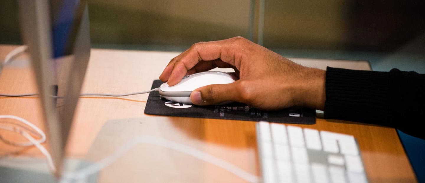 A hand using a computer mouse on a desk