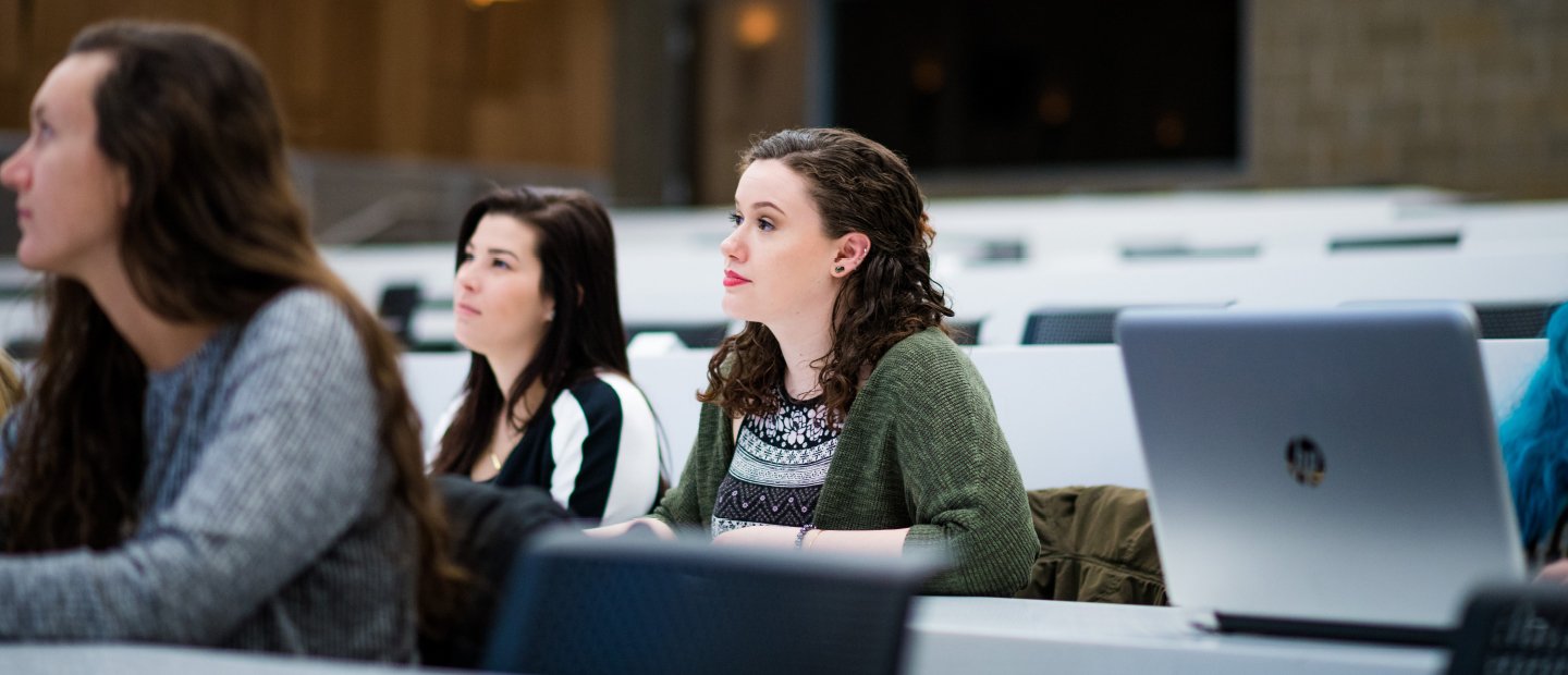 Three female students seated in a lecture hall