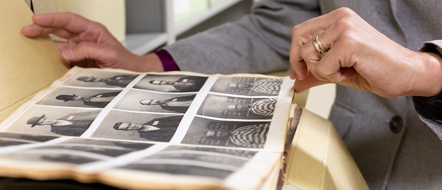 person flipping through a folder of old black and white photos of people