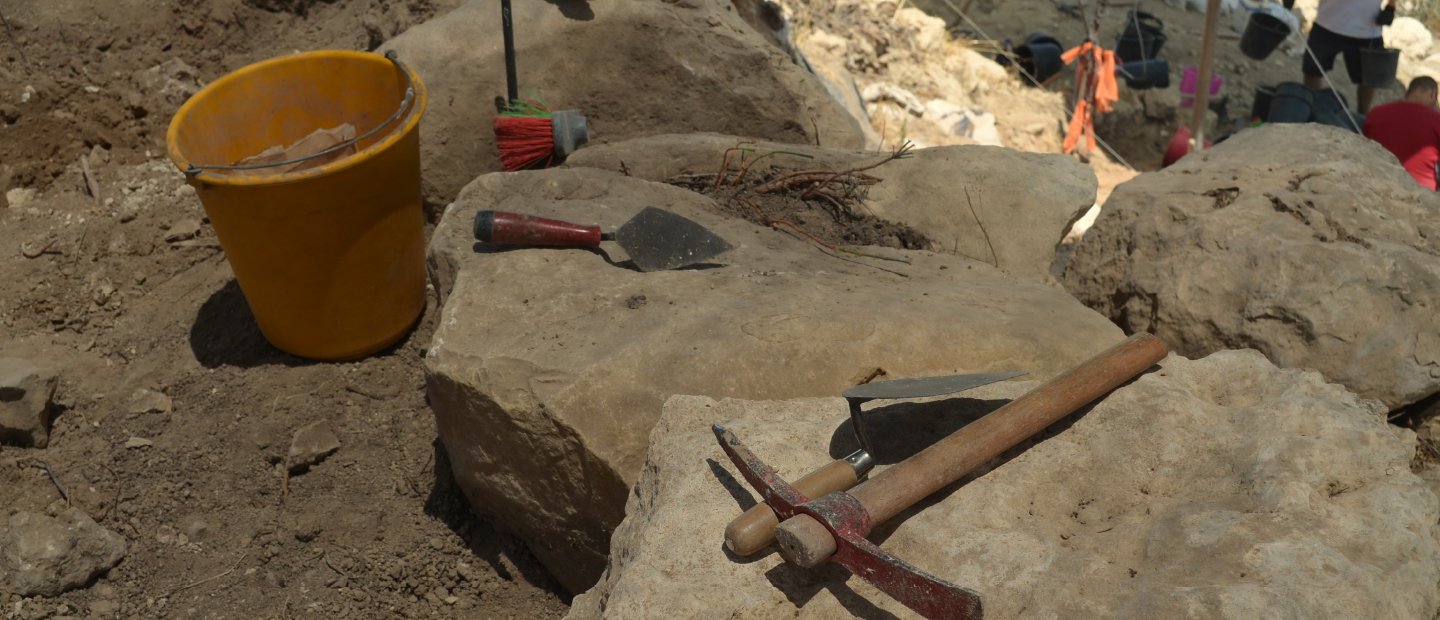 Tools sitting on rocks at an archaeological dig site.
