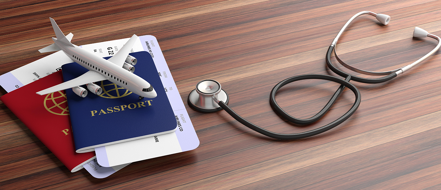 Two passports, a small model of an airplane and a stethoscope on a table.