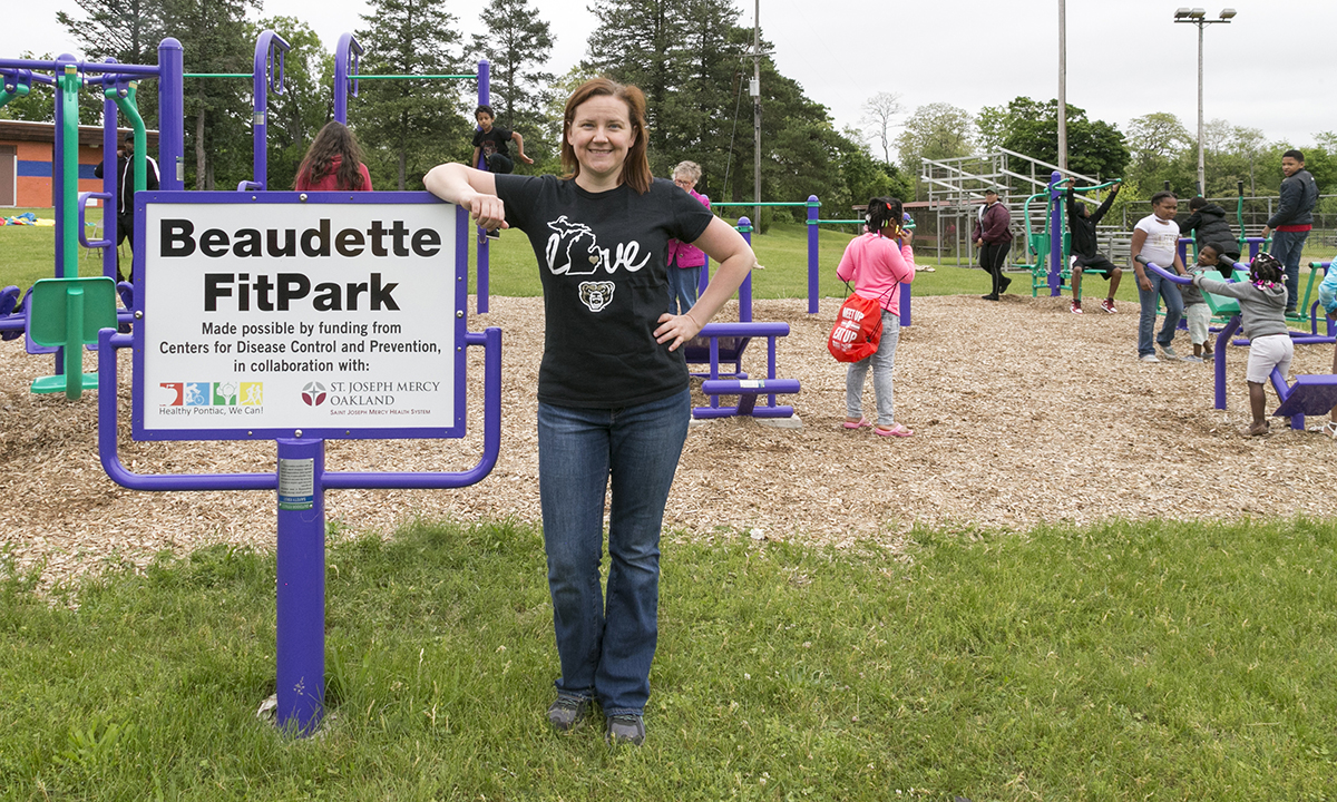 A woman standing next to a sign in front of a children's park