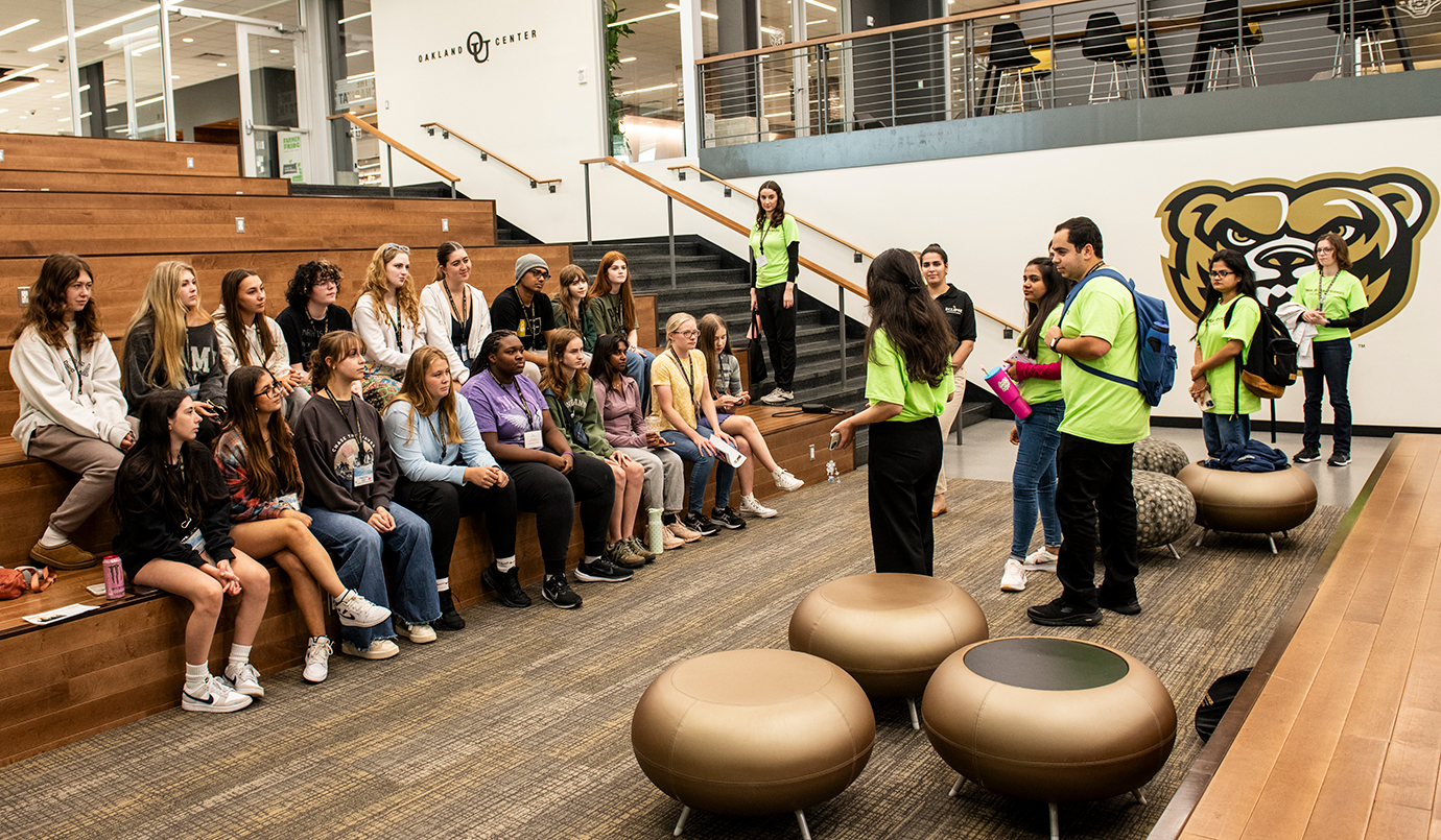 Summer camp instructors talk to students listening attentively in the Oakland Center