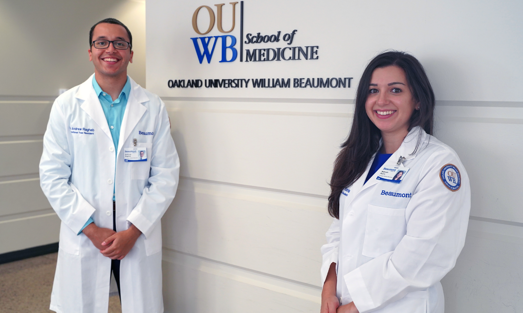 An image of OUWB alumni posing in front of an OUWB sign.