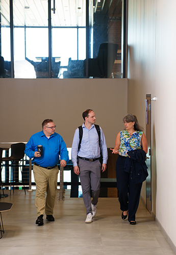 Jordan Kehoe and 2 EMBA cohort members walking down the hallway