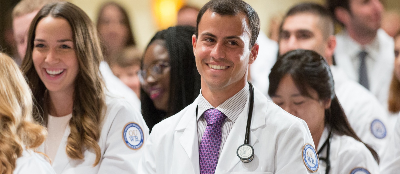 A student smiles as he stands in the crowd at the White Coat ceremony.