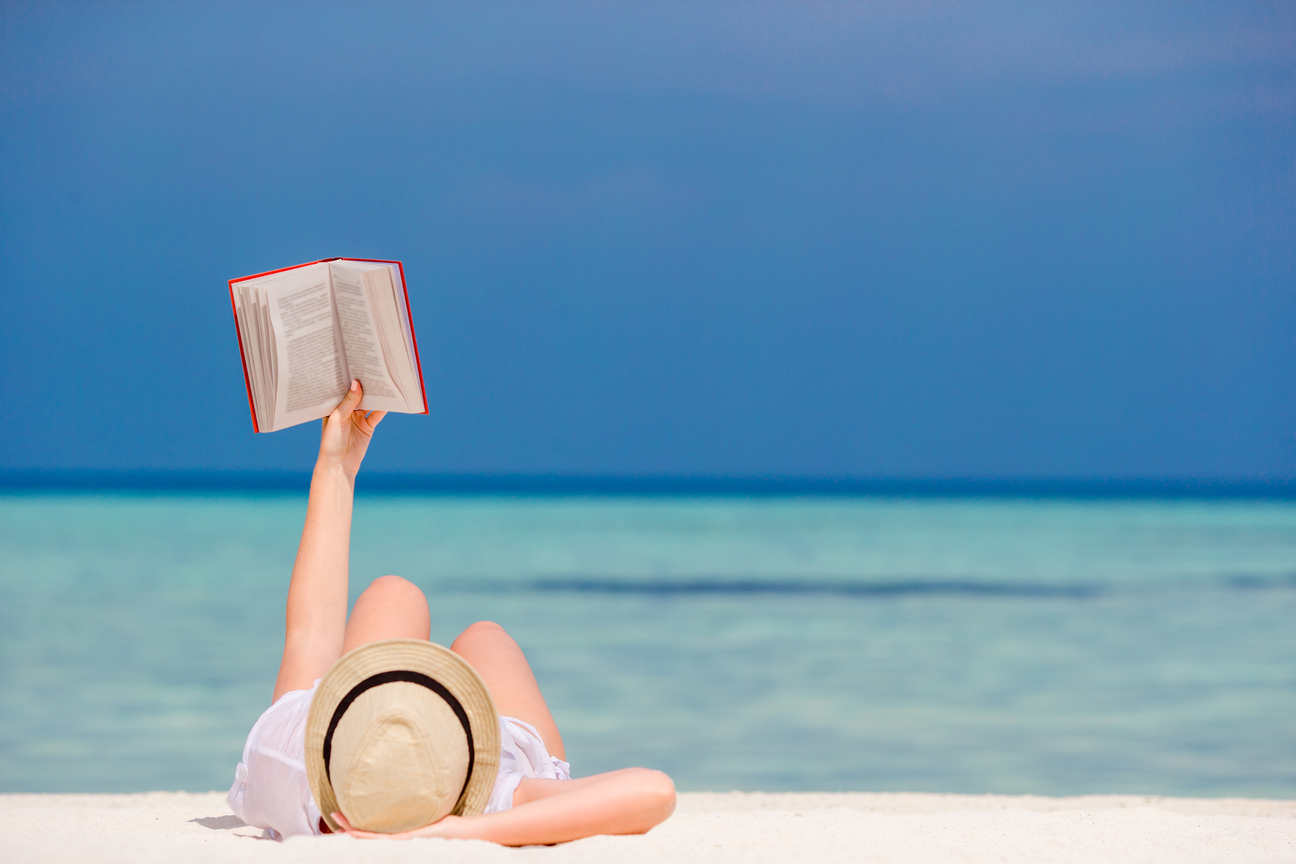A person reading a book on a beach