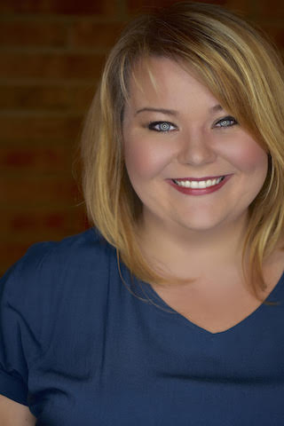 Headshot of Elise Eden in a blue shirt in front of a brick background