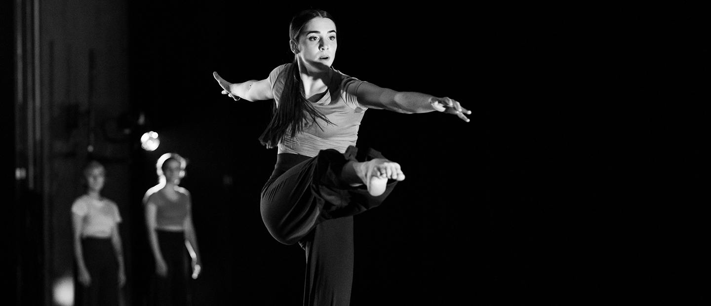 image of a solo female dancer onstage with her leg extended