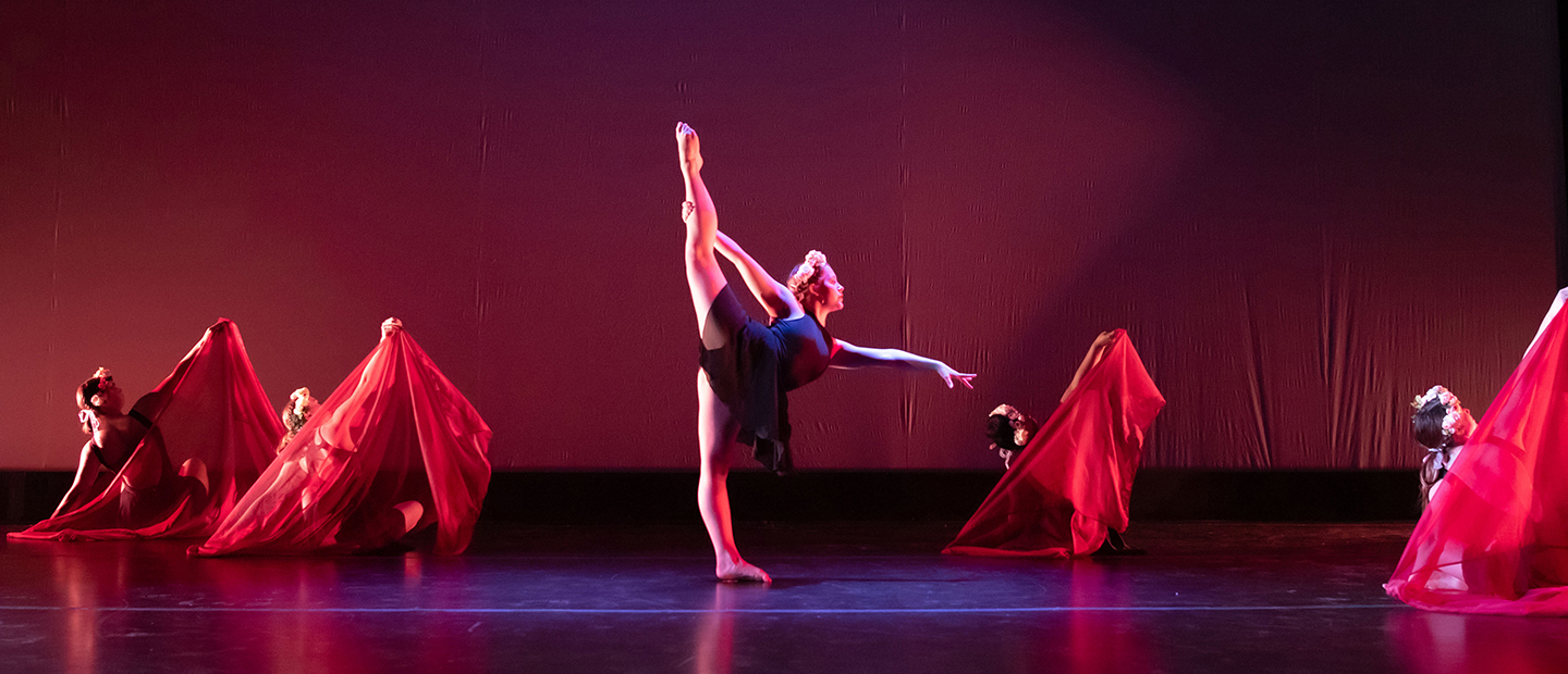 image of one dancer with her leg extended and four dancers in the background