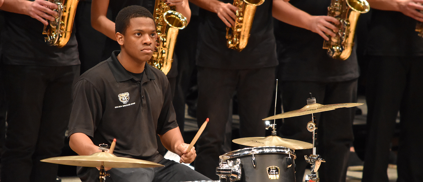 image of a young man playing the drum set in an orchestral group