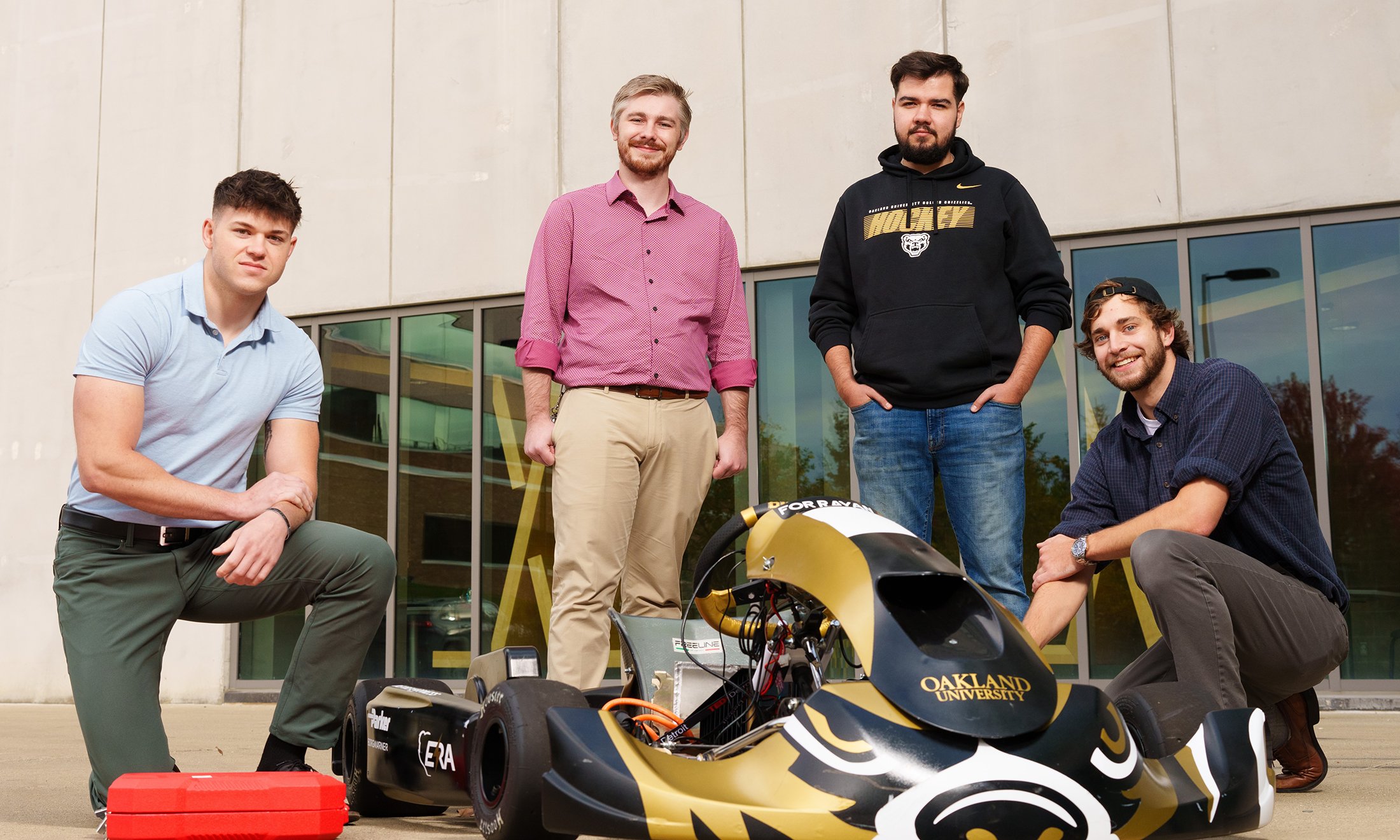 Four students standing behind a race kart