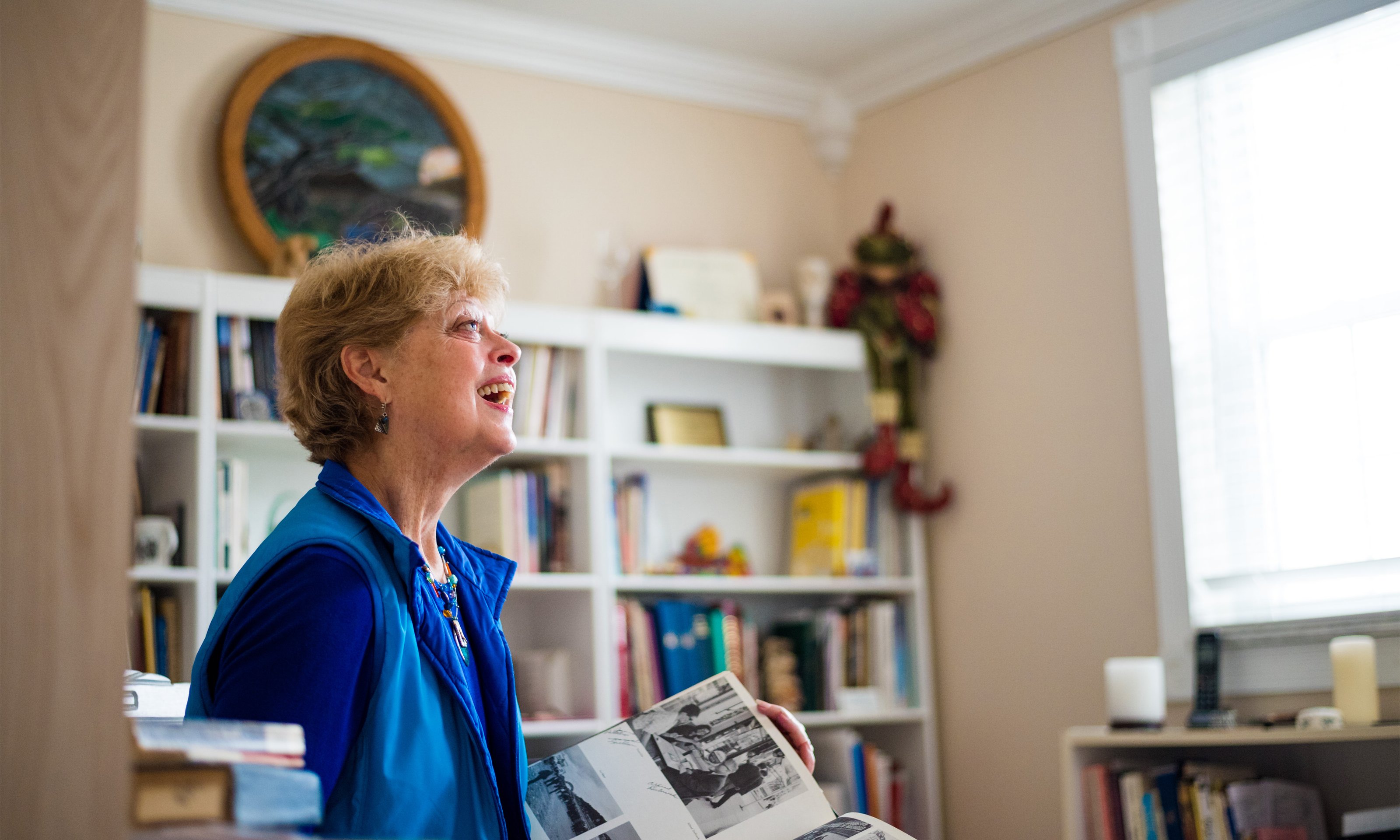 Oakland University alumna Kate Thoresen looks at an old yearbook in her home