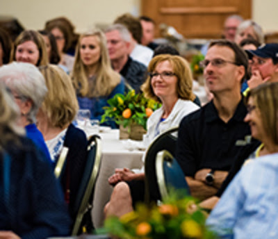A group of O U faculty and staff members sitting at a banquet table looking towards a presenter who's not pictured