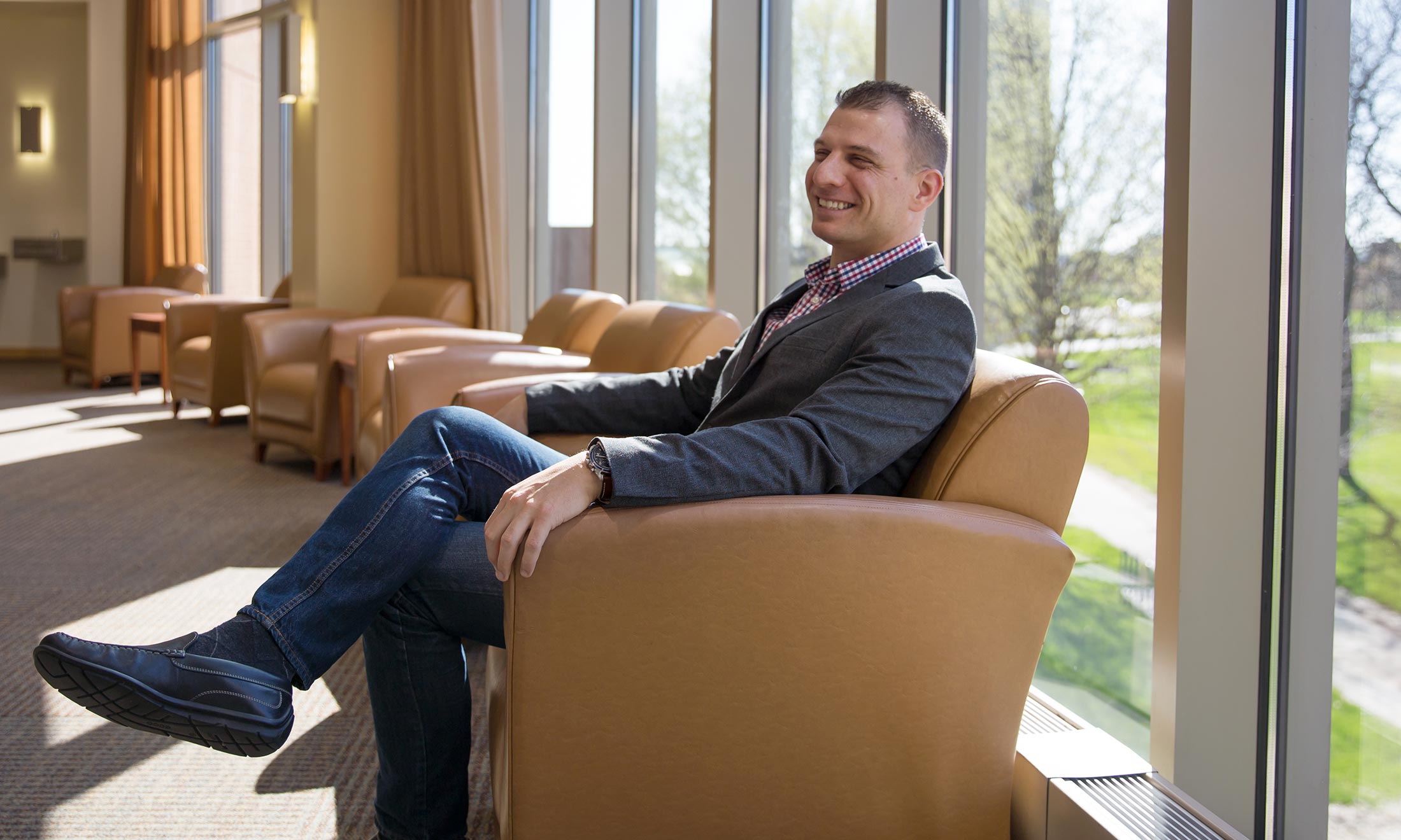 Oakland University graduate Sean Kosofsky sits in a chair inside the Oakland Center on campus