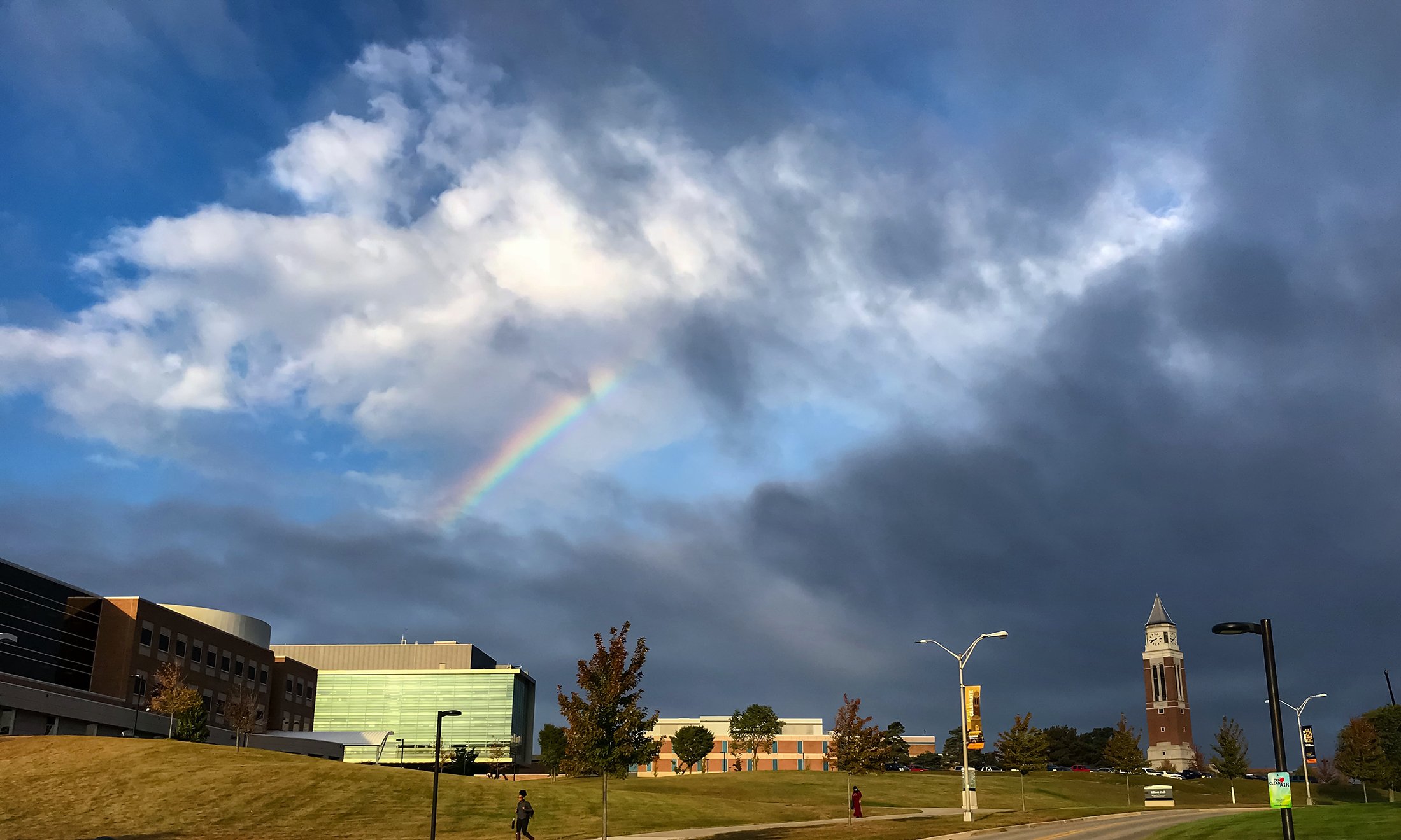 Color photo of rainbow in the sky over the Engineering Center. Storm clouds to the right over the Elliott Tower.