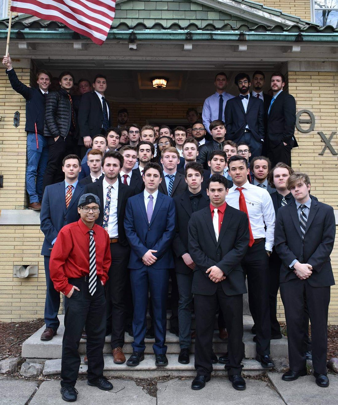 Members of Theta Chi Fraternity standing outside the fraternity house