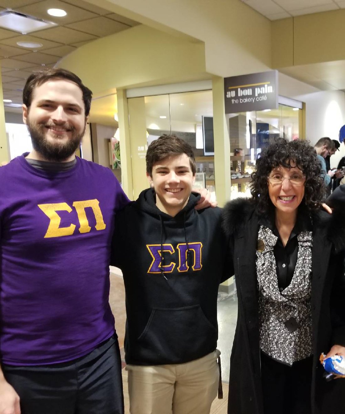Members of Sigma Pi fraternity standing with OU President Ora Hirsch Pescovitz in the Oakland Center