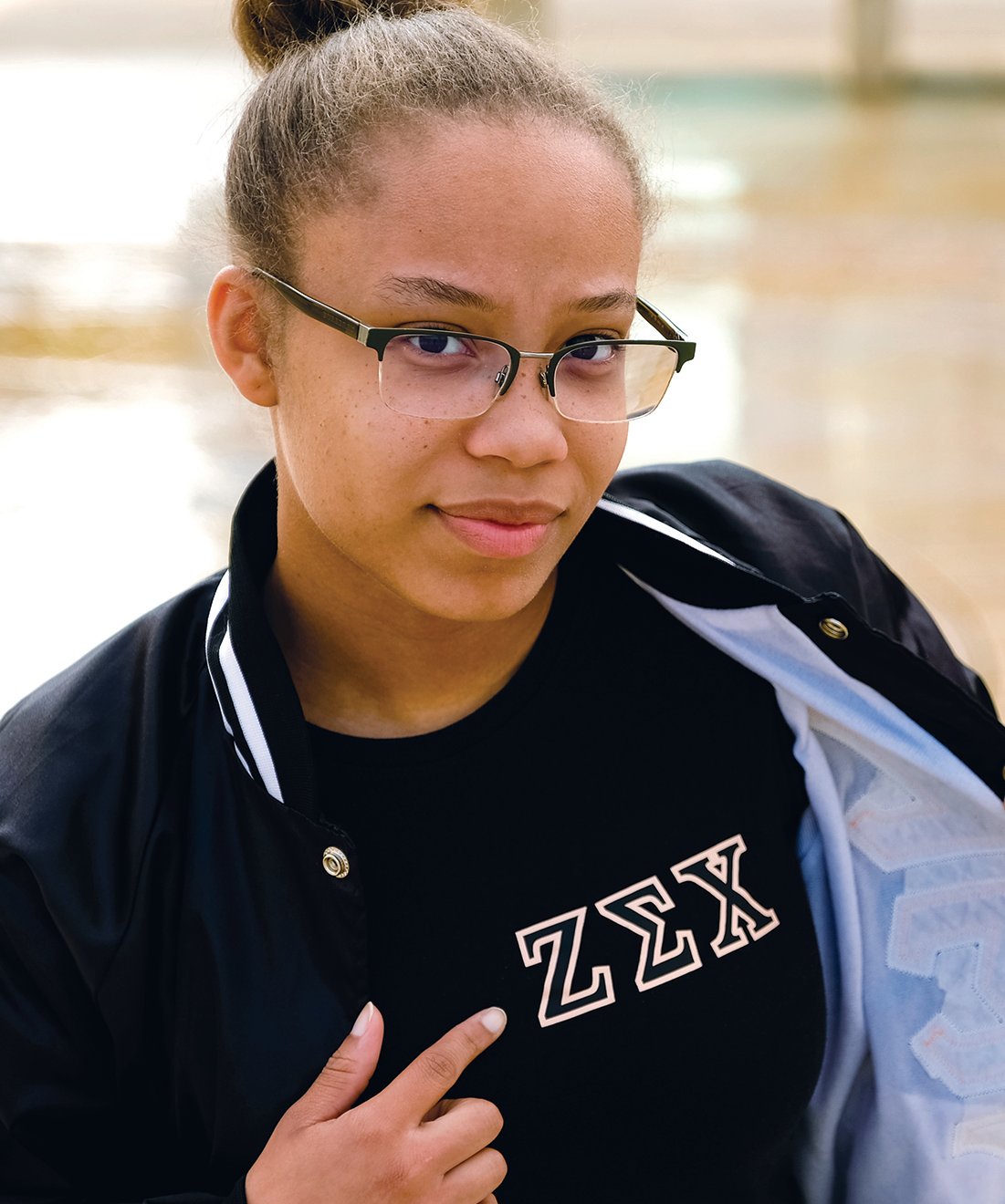One member of Zeta Sigma Chi sorority looking at camera and pointing to the sorority letters on her shirt