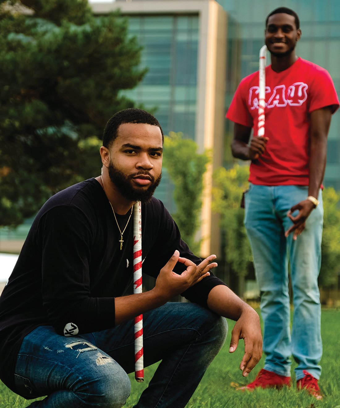 Two members of Kappa Alpha Psi fraternity on campus while showing fraternity letters with their hands
