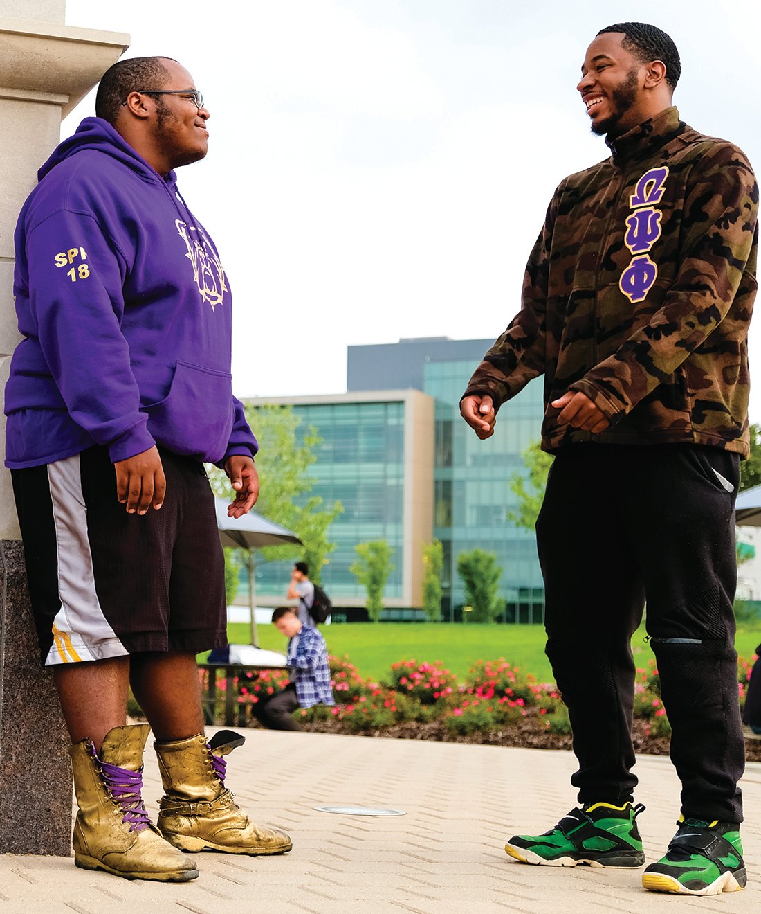 Two members of Omega Psi Phi talking next to Elliott Tower on campus