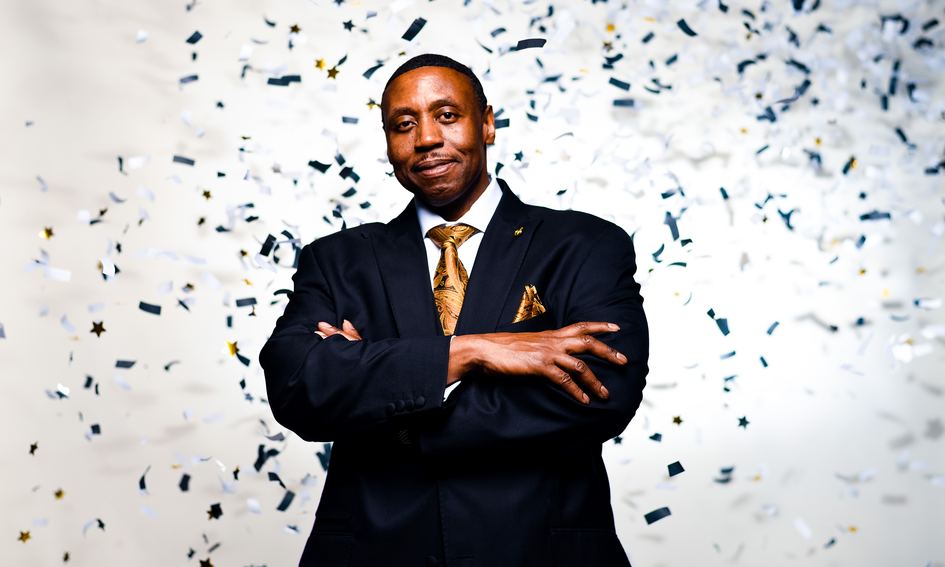 Oakland University Vice President for Student Affairs and Chief Diversity Officer Glenn McIntosh in front of a white screen with gold and black graffiti around him. 
