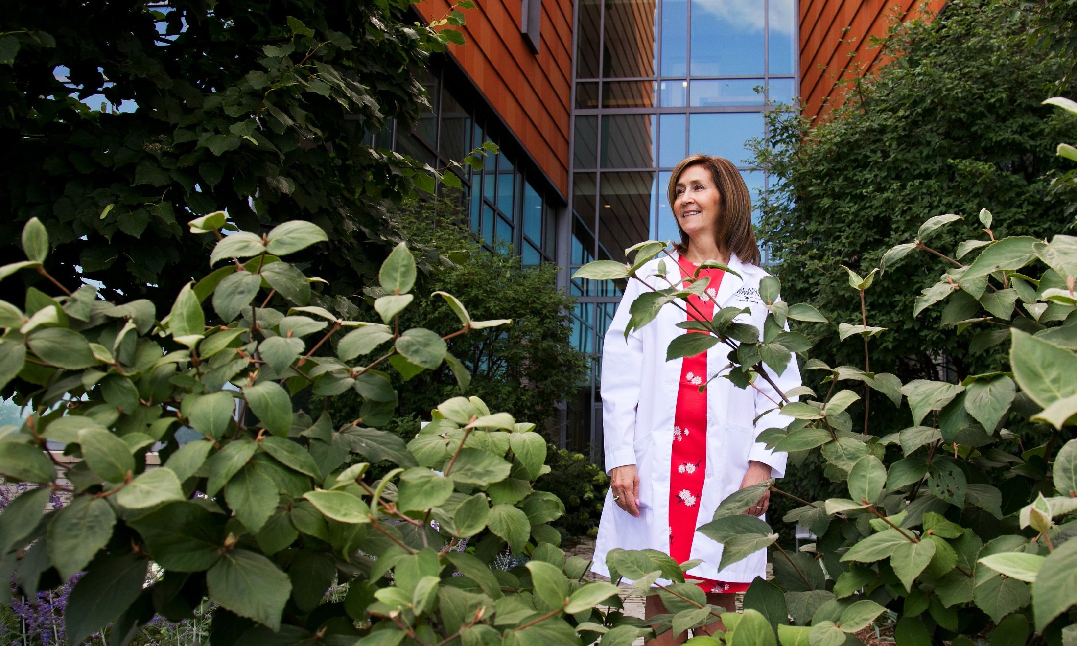 Andrea Bittinger standing behind some greenery outside of a building