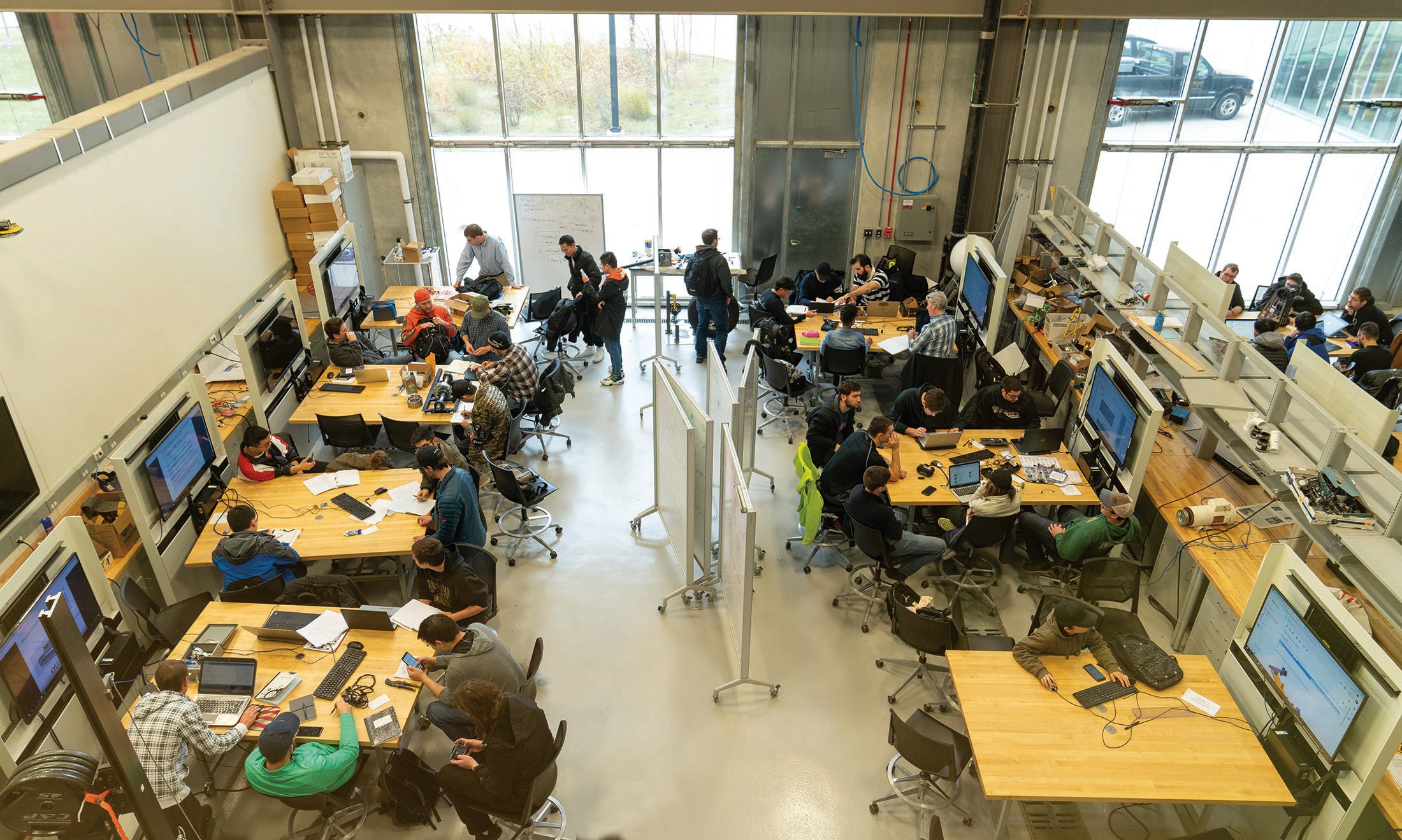classroom of students sitting at tables in the engineering building senior design course lab.
