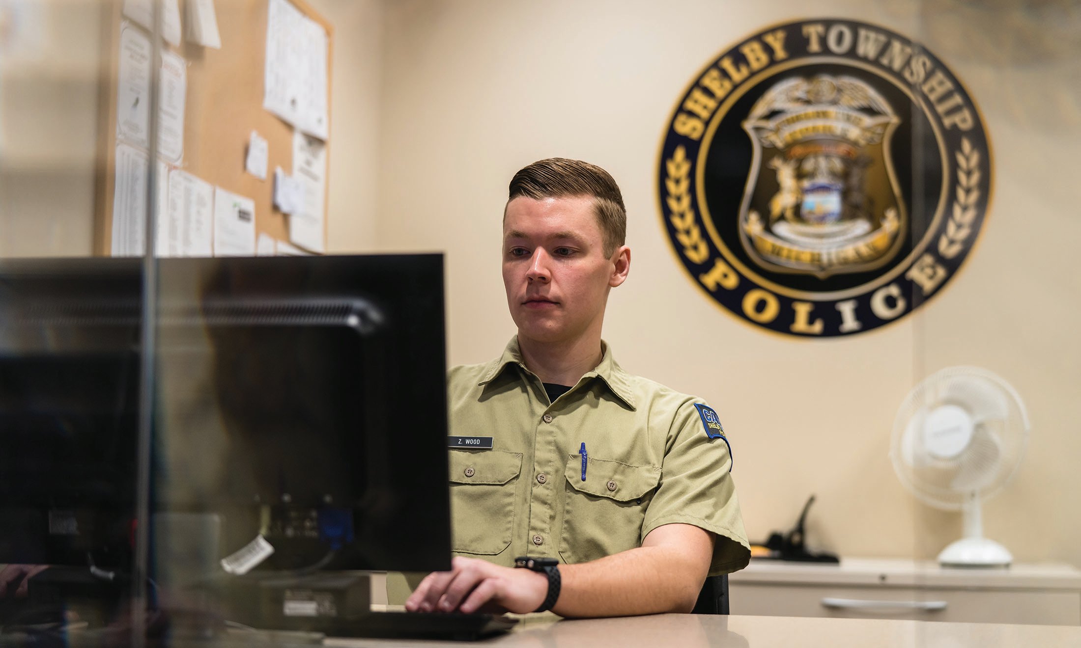 Male student sits at computer in Shelby Township Police Department