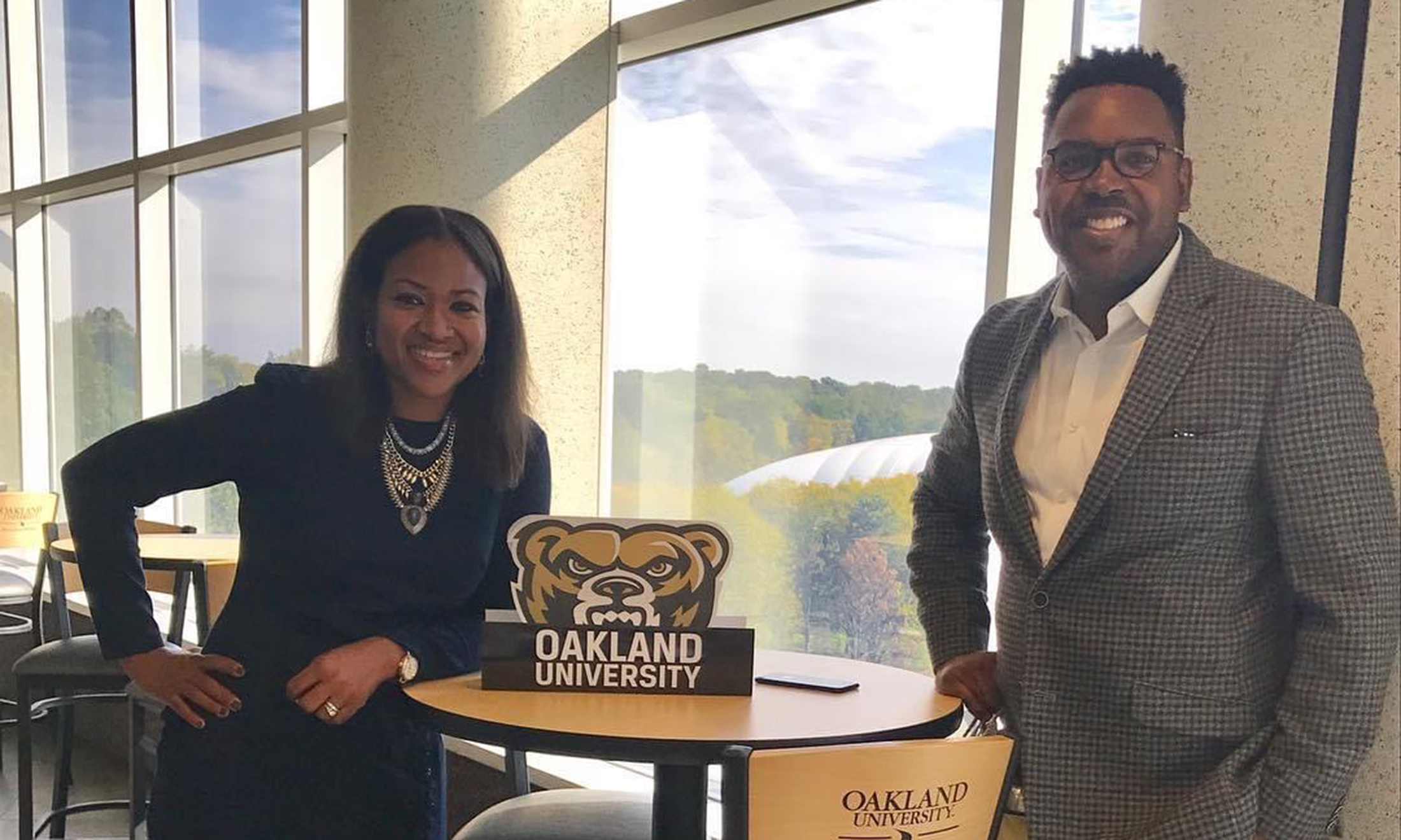 A photo of Stefen andKaniqua Welch leaning on a table that has a Grizzhead decoration that says "Oakland University"