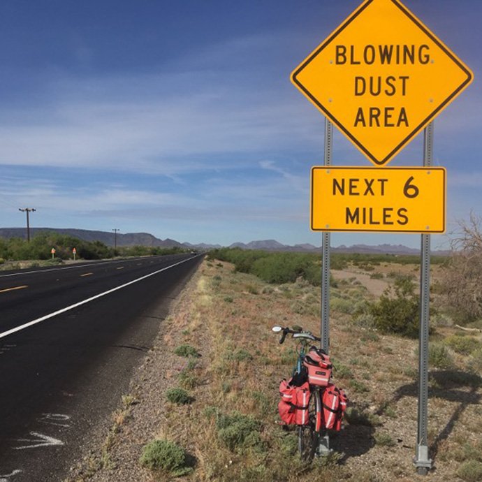 Bike and road with road sign that states "Blowing dust area next 6 miles"