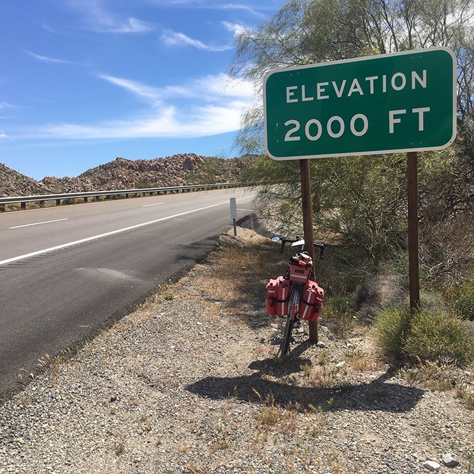 Road and bicycle with road sign that states "elevation 2000 ft"