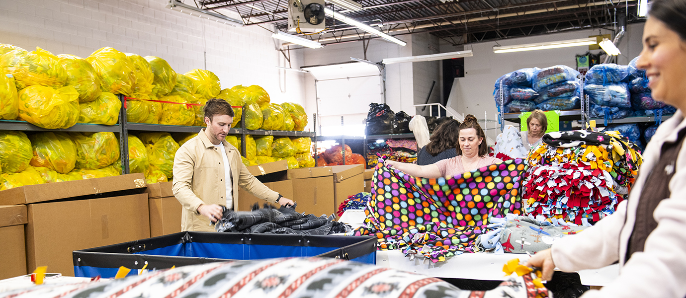 People standing in warehouse folding blankets