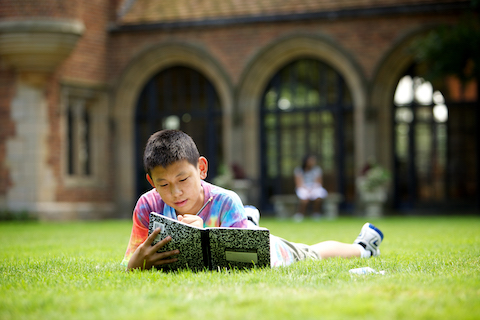 student studying on meadow brook hall grass