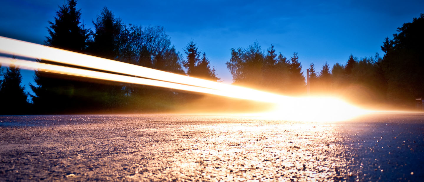 Car headlights beaming over a road at night