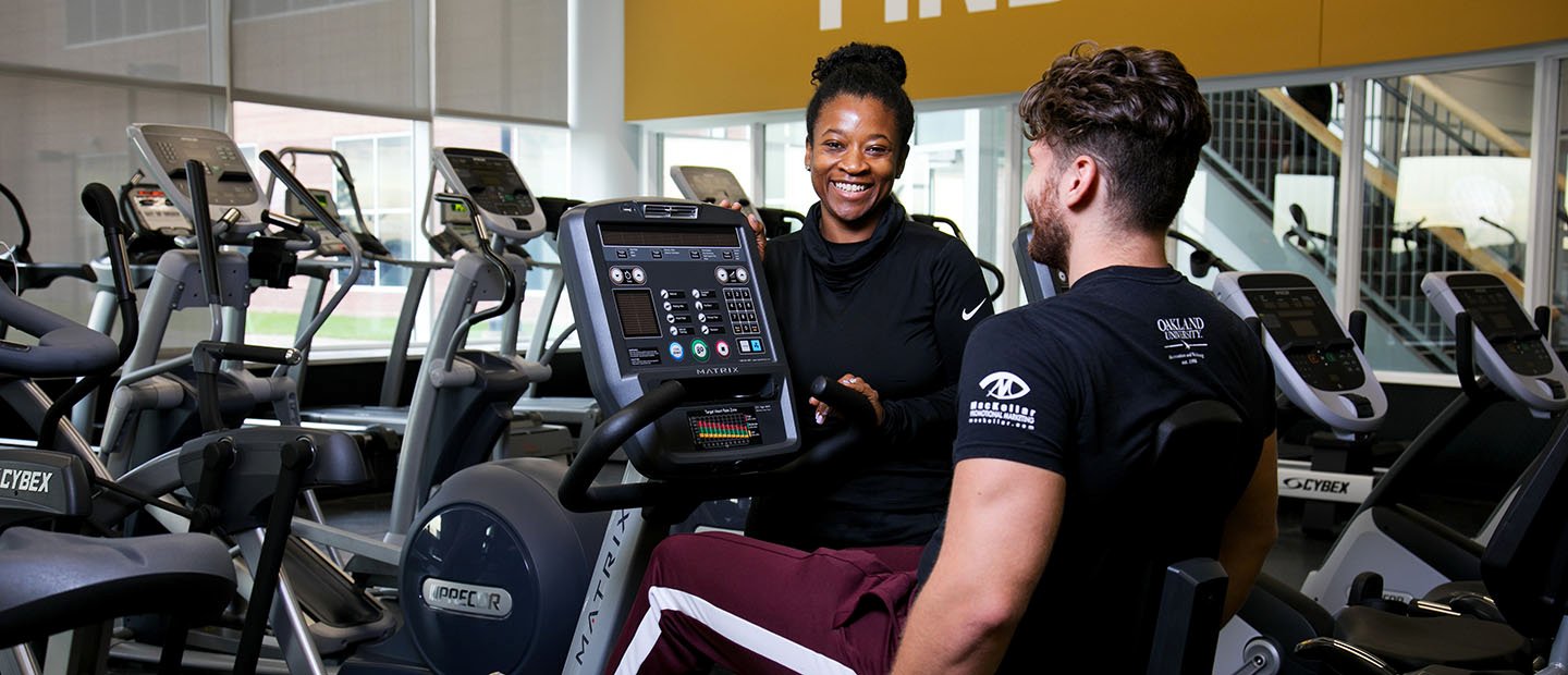 trainer working with a client on an exercise bike in a fitness center