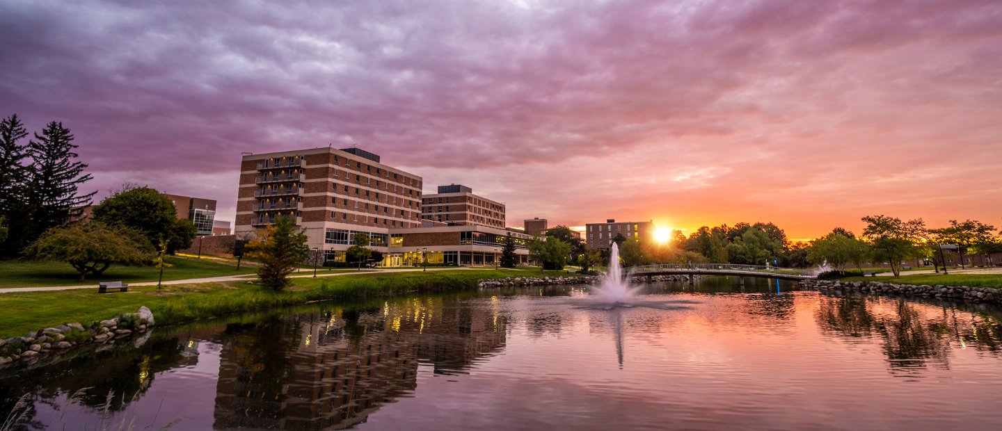 Bear Lake and buildings on Oakland University's campus with a purple and orange sky.