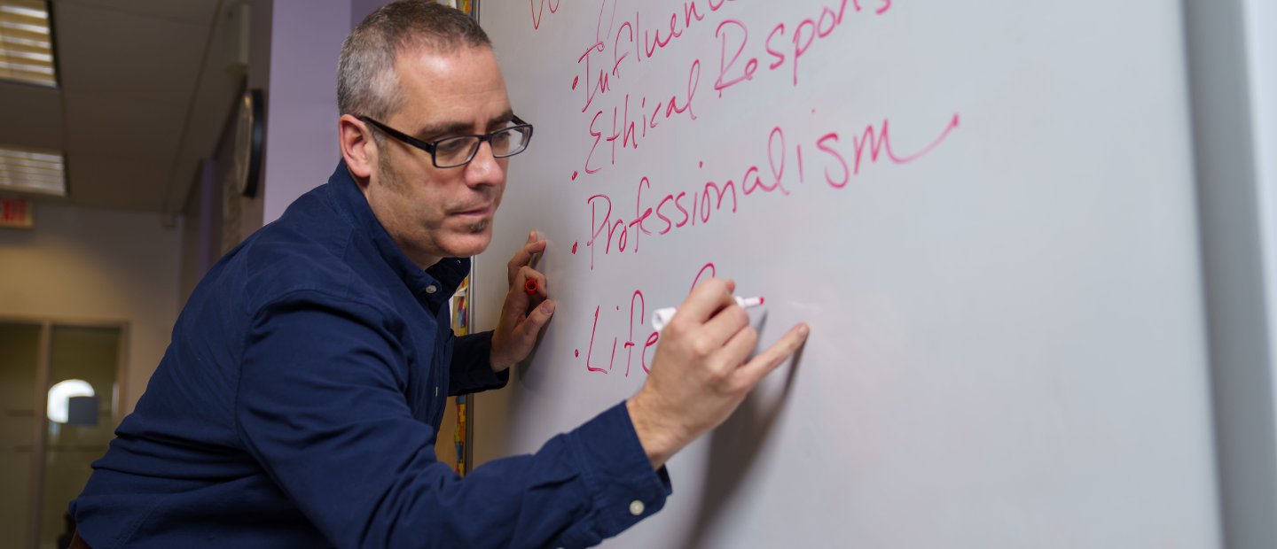 A professor writing on a white board.