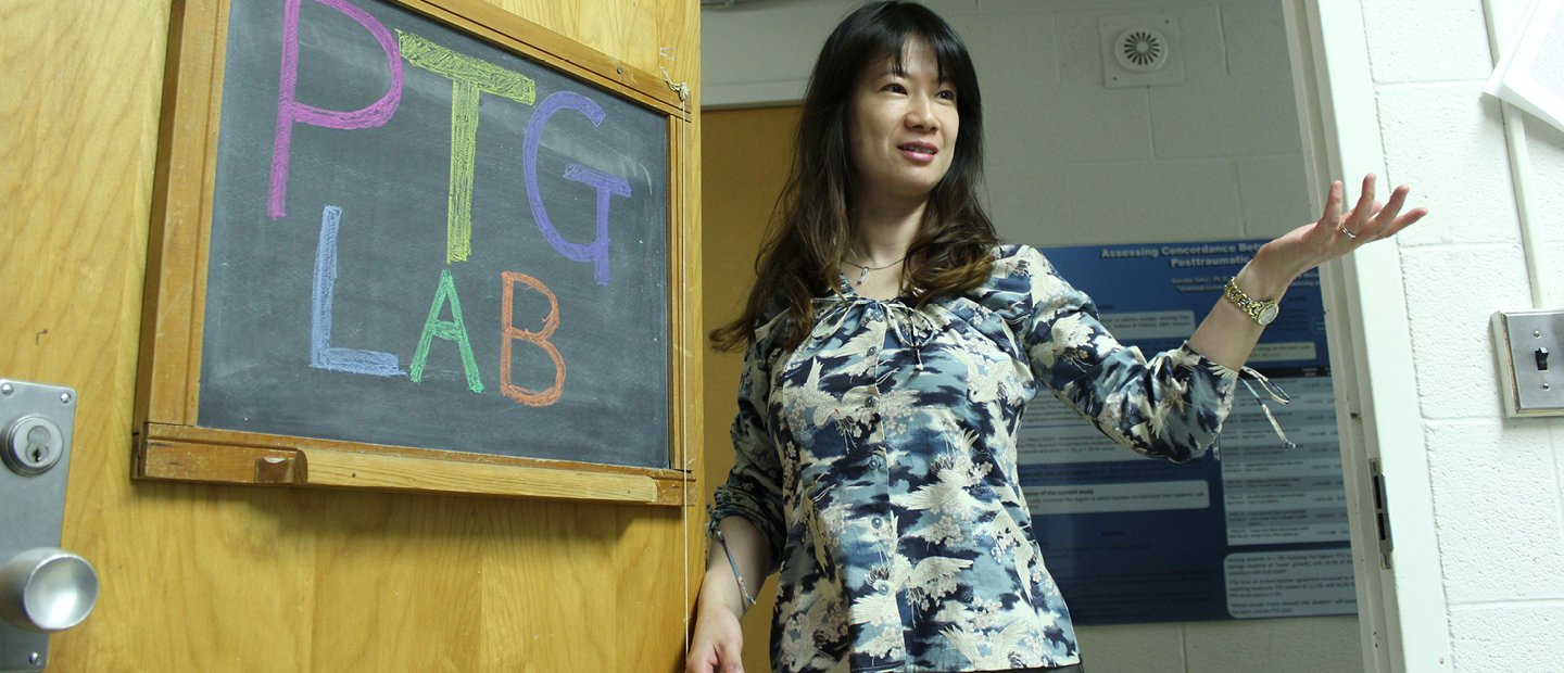  A professor standing in front of a chalk board with writing that says "P T G Lab".